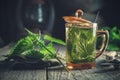 Healthy nettle tea, nettle plants, gloves and garden pruner on old wooden table.