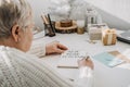 Healthy New Years resolutions for older adults. Senior mature old woman in white sweater writing handwritten text New Royalty Free Stock Photo