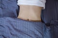 Healthy nutrition and belly health concept. Close up of woman flat stomach. Girl in bed with hungry feeling. Top view Royalty Free Stock Photo