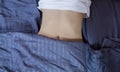 Healthy nutrition and belly health concept. Close up of woman flat stomach. Girl in bed with hungry feeling. Top view. Banner Royalty Free Stock Photo