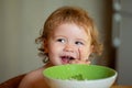 Healthy nutrition for kids. Funny baby eating food himself with a spoon on kitchen. Royalty Free Stock Photo