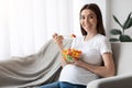 Healthy Nutrition During Pregnancy. Happy Pregnant Woman Sitting On Couch, Enjoying Salad Royalty Free Stock Photo