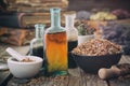 Dry oak bark in bowl, infusion or tincture bottles. Mortar and bowls of medicinal herbs and books on background. Herbal