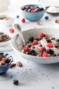 Healthy oat yoghurt bowl with berries, nuts, seeds and granola for fixings.