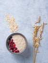 Healthy oats porridge with cranberries on light blue background with oatmeal ears. Healthy breakfast diet food