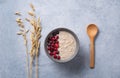 Healthy oats porridge with cranberries on light blue background with oatmeal ears and wood spoon. Healthy breakfast diet food