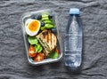 Healthy office lunch box - boiled egg, avocado, tuna spinach cheese sandwiches, tomatoes and bottle pure water on a gray Royalty Free Stock Photo