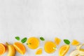 Healthy orange banana smoothie bottom border, top view over a white marble background with copy space