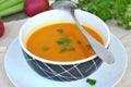 Healthy orange soup from pumpkin hokaido, green celery, garlic, onion and parsley in boxl with spoon on brown cloth and wooden