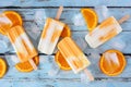 Healthy orange yogurt popsicles, top view over rustic blue wood