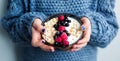 Healthy organic breakfast. Child in woolen classic blue colored sweater holding bowl of of muesli and yoghurt with fresh berries Royalty Free Stock Photo