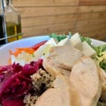 Healthy Organic Salad with Chicken Slices, Avocado, Goat Cheese, Arugula Leaves and Quinoa Served with Olive Oil and Vinegar