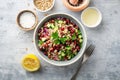 Healthy pearl barley salad with beans, cucumbers, red onion, sunflower seeds, pomegranate and parsley in bowl