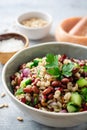 Healthy pearl barley salad with beans, cucumbers, red onion, sunflower seeds, pomegranate and parsley in bowl