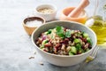 Healthy pearl barley salad with beans, cucumbers, red onion, sunflower seeds, pomegranate and parsley in bowl