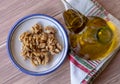 Healthy peeled nuts on a ceramic plate accompanied by a bottle of extra virgin olive oil. Top view