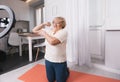 a healthy pensioner sits on the bedroom floor in front of a tripod for a camera, shoots a fitness video tutorial for the