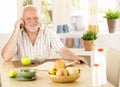 Healthy pensioner using cellphone at breakfast