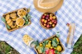 Picnic for summer holidays with fresh pastries, fresh fruits and berries, laid out on a white-blue checked fabric, basket and hat Royalty Free Stock Photo