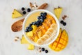 Pineapple, mango smoothie bowl with coconut, bananas, blueberries and granola, above view on a bright background Royalty Free Stock Photo