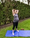 Healthy pregnant woman doing yoga with dumbbells in nature outdoors. Royalty Free Stock Photo