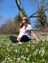 A healthy pregnant Woman is doing yoga in the Park surrounded by Beautiful snowdrops Royalty Free Stock Photo