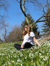 A healthy pregnant Woman is doing yoga in the Park surrounded by Beautiful snowdrops Royalty Free Stock Photo