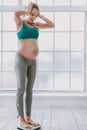 Healthy pregnant woman in sportwear measuring her weight Royalty Free Stock Photo