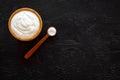 Healthy product, healthy meal. Greek yogurt in brown bowl near spoon on black background top view copy space