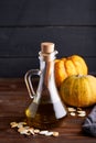 Healthy pumpkin oil in glass bottles. Dark wooden background Copy space