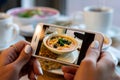 Young woman hands make photo of pumpkin and carrot soup. Take social networks smartphone food photography. Royalty Free Stock Photo