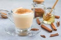 Healthy rooibos red tea latte topped with cinnamon, in glass cup and ingredients on background Royalty Free Stock Photo