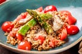 Healthy salad of barley porridge with asparagus, tomatoes and mushrooms on plate. Vegan food.