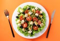 Healthy salad of cherry tomatoes, cucumbers, peppers, black olives, with olive oil, quail eggs and gorgonzolla cheese on a orange