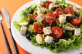 Healthy salad of cherry tomatoes, cucumbers, peppers, black olives, with olive oil, quail eggs and gorgonzolla cheese on a orange