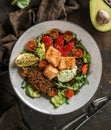 Healthy salad with fillet salmon, quinoa, avocado sauce, grilled pepper, tomatoes, lettuce, arugula in plate on wooden background Royalty Free Stock Photo