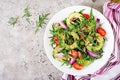 Healthy salad of fresh vegetables - tomatoes, avocado, arugula, radish and seeds