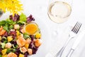 Healthy salad with prawns, lettuce, oranges and mango served on a plate with orange mustard sauce