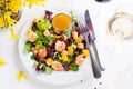 Healthy salad with prawns, lettuce, oranges and mango served on a plate with orange mustard sauce