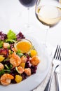 Healthy salad with prawns, lettuce, oranges and mango served on a plate with orange mustard sauce