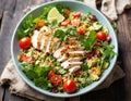 Healthy salad with quinoa, cherry tomatoes, chicken meat, avocado, lime and mixed greens, lettuce, parsley on a wooden table. Royalty Free Stock Photo