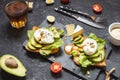 Healthy sandwich - poached eggs and avocado on toast with tomatoes on black stone background