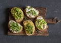 Healthy sandwiches with avocado, hummus, ricotta, cucumber, sunflower sprouts, micro greens and flax seeds. On wooden background,