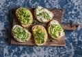 Healthy sandwiches with avocado, hummus, ricotta, cucumber, sunflower sprouts, micro greens and flax seeds. On a wooden cutting bo
