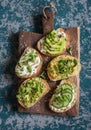 Healthy sandwiches with avocado, hummus, ricotta, cucumber, sunflower sprouts, micro greens and flax seeds. On a wooden cutting bo