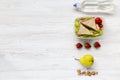 Healthy school lunch box with fresh fruits, walnuts, organic vegetables sandwiches and bottle of water on white wooden background, Royalty Free Stock Photo