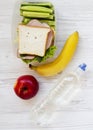 Healthy school lunch box with fresh organic vegetables sandwich, fruits and bottle of water on white wooden table, overhead view. Royalty Free Stock Photo