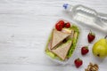 Healthy school lunch box with fresh organic vegetables sandwiches, walnuts, bottle of water and fruits on white wooden background, Royalty Free Stock Photo