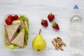 Healthy school lunch box with fresh organic vegetables sandwiches, walnuts, bottle of water and fruits on white wooden background, Royalty Free Stock Photo