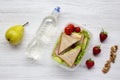 Healthy school lunch box with fresh organic vegetables sandwiches, walnuts, bottle of water and fruits on white wooden background, Royalty Free Stock Photo